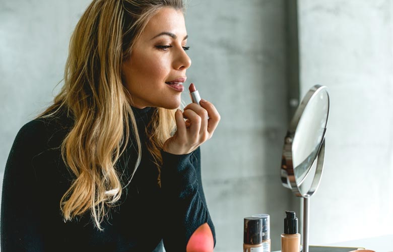 woman applying lipstick in mirror