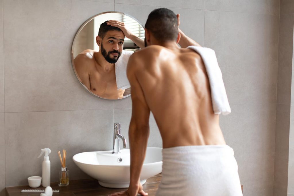 man looking in mirror at face